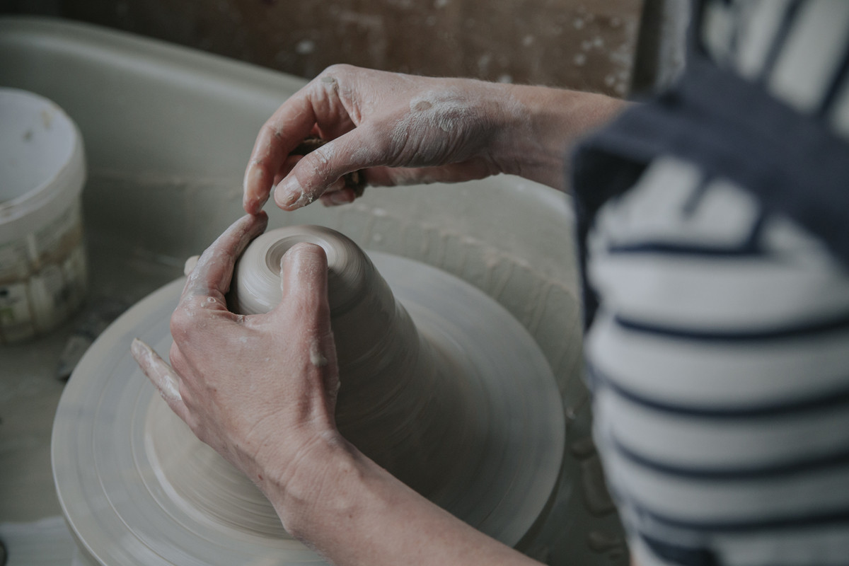 Potter's hands throwing a pot on the wheel